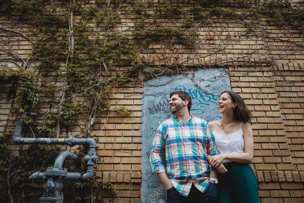 man and woman leaning against a wall with graffiti
