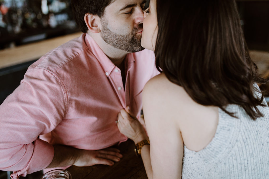 man and woman kissing in a bar