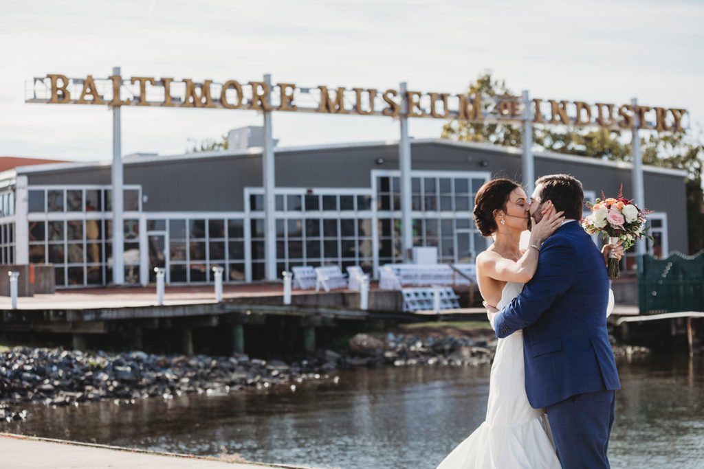 a bride and groom kiss in front of the Baltimore museum of industry