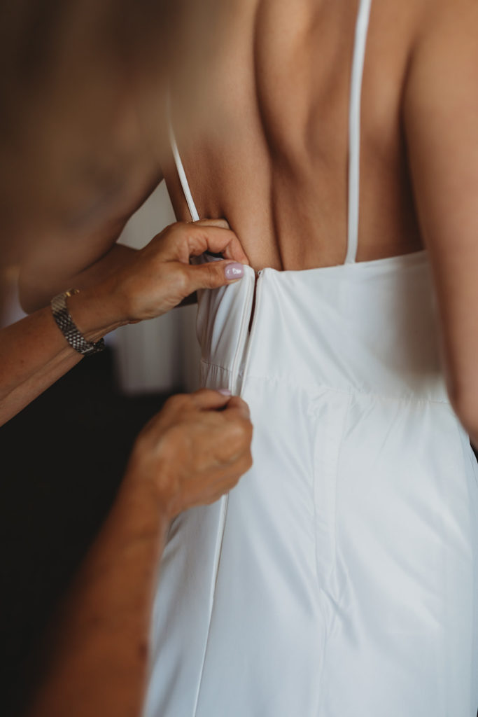 a mother zips up her daughters wedding dress